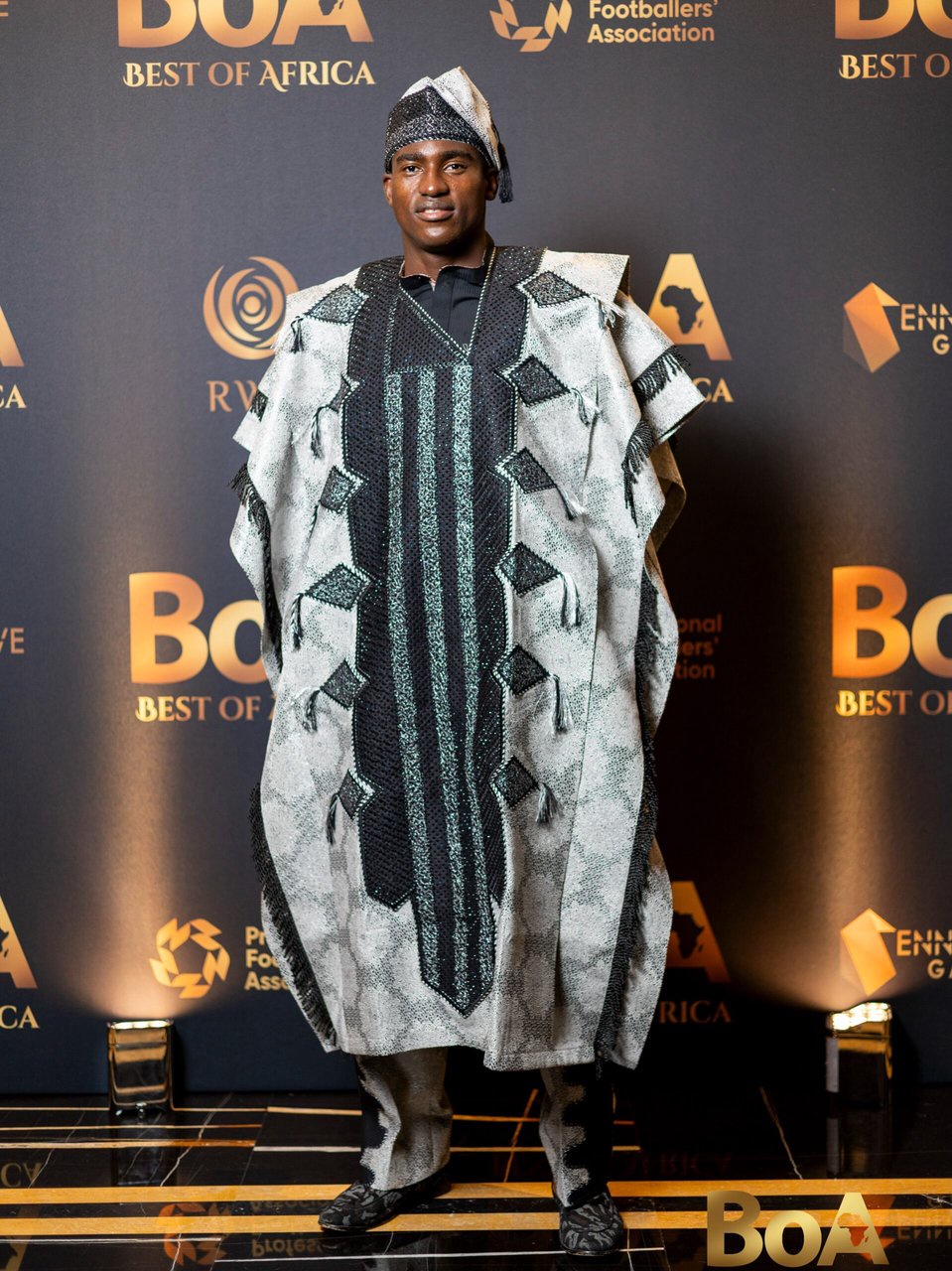 Taiwo Awoniyi on the red carpet in a silver and black embroidered Agbada and Fila at the Best of Africa Awards 2026.