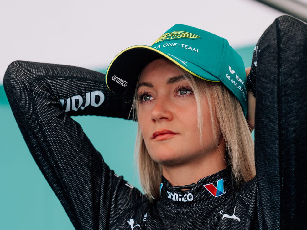 person wearing a teal racing cap and black racing suit.