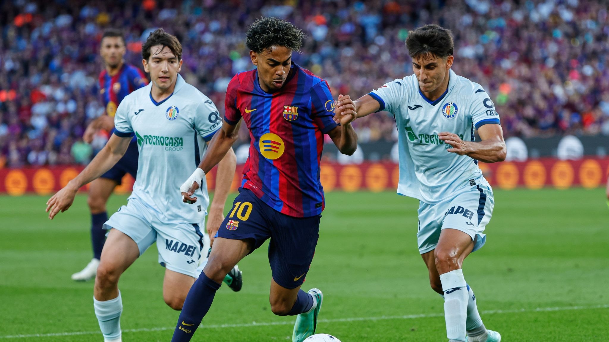 Barcelona's Lamine Yamal, centre, challenges for the ball with Getafe's Ramon Terrats, right, during the Spanish La Liga soccer match between Barcelona and Getafe in Barcelona, Spain, Saturday, Oct. 10, 2026. (AP Photo/Joan Monfort)
