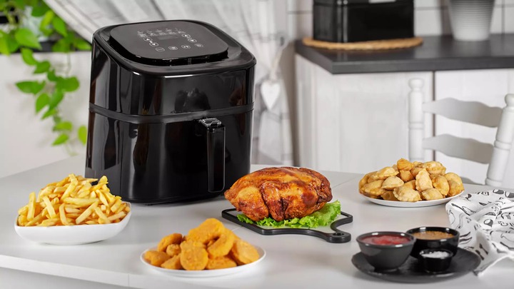 Air fryer with foods around it on the table