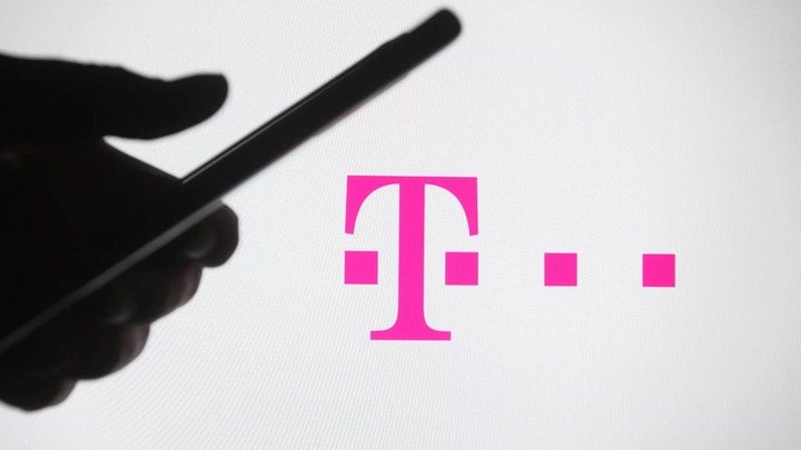 A person holding a phone next to the T-Mobile logo