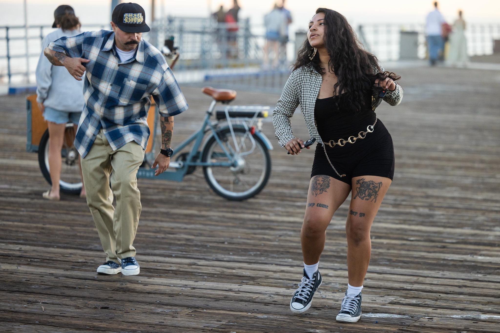 Two people dance on the Santa Monica Pier during Locals Night, celebrating the 50th anniversary of the Dogtown Z-Boys skate team era.