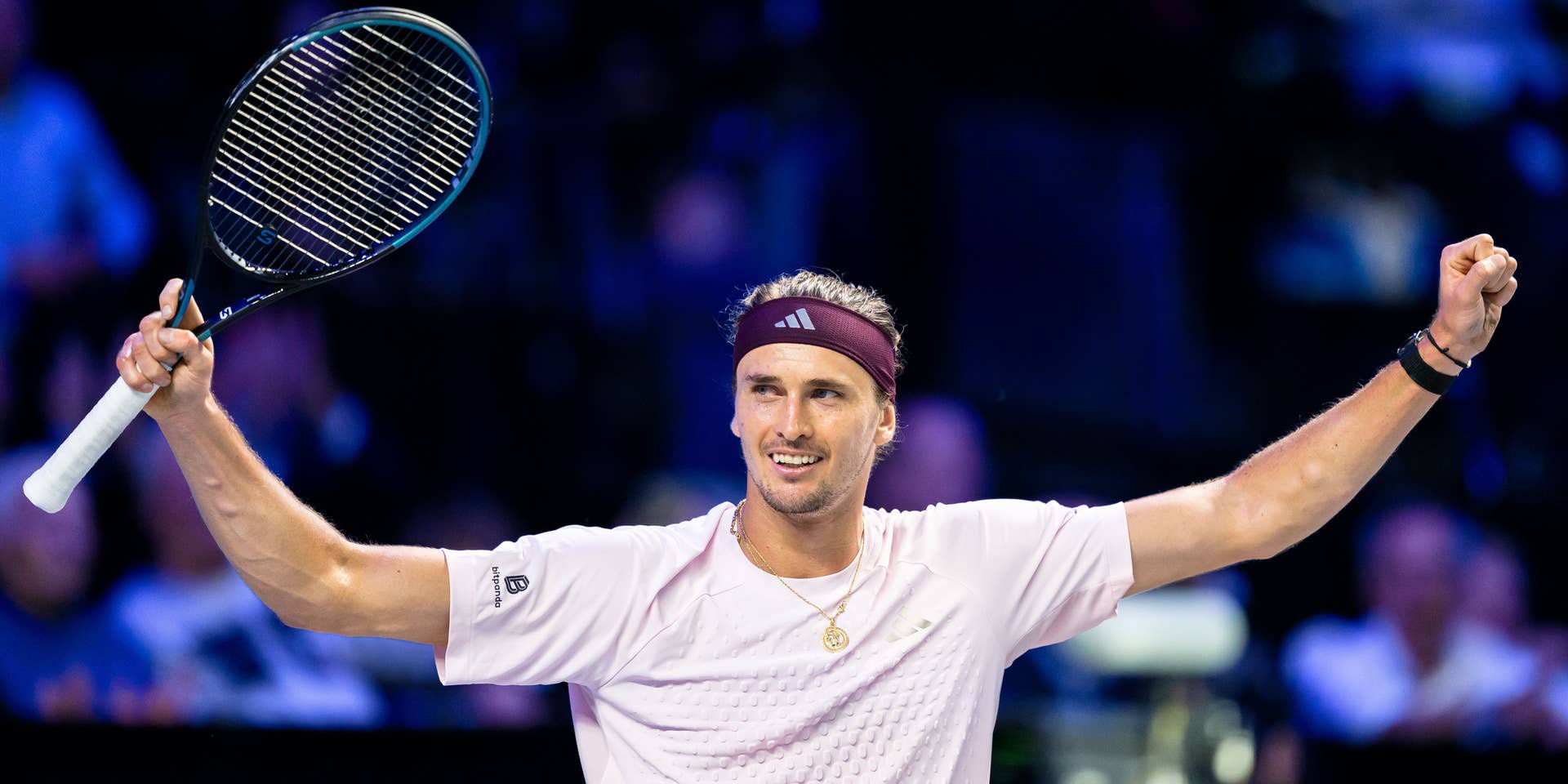 Alexander Zverev jubelt mit erhobenem Schläger und geballter Faust im hellrosa Trikot auf dem Tennisplatz.