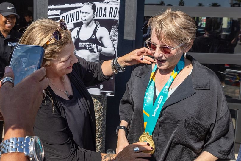 Watch Me! Sports Bar Co-owners Emme Eddy, center, places Olympic medals from rower Maddy Focht, left, of Long Beach, on Jax Diener, right center, during the grand opening in Long Beach Friday, July 26, 2024