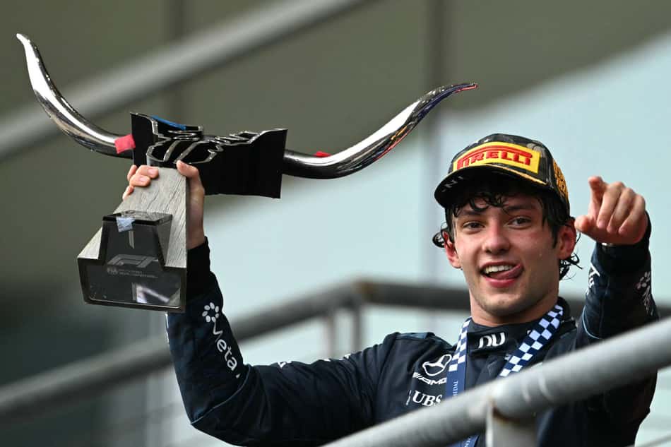 Kimi Antonelli no pódio do GP dos EUA de F1, erguendo troféu e sorrindo (Foto: RONALDO SCHEMIDT / AFP)