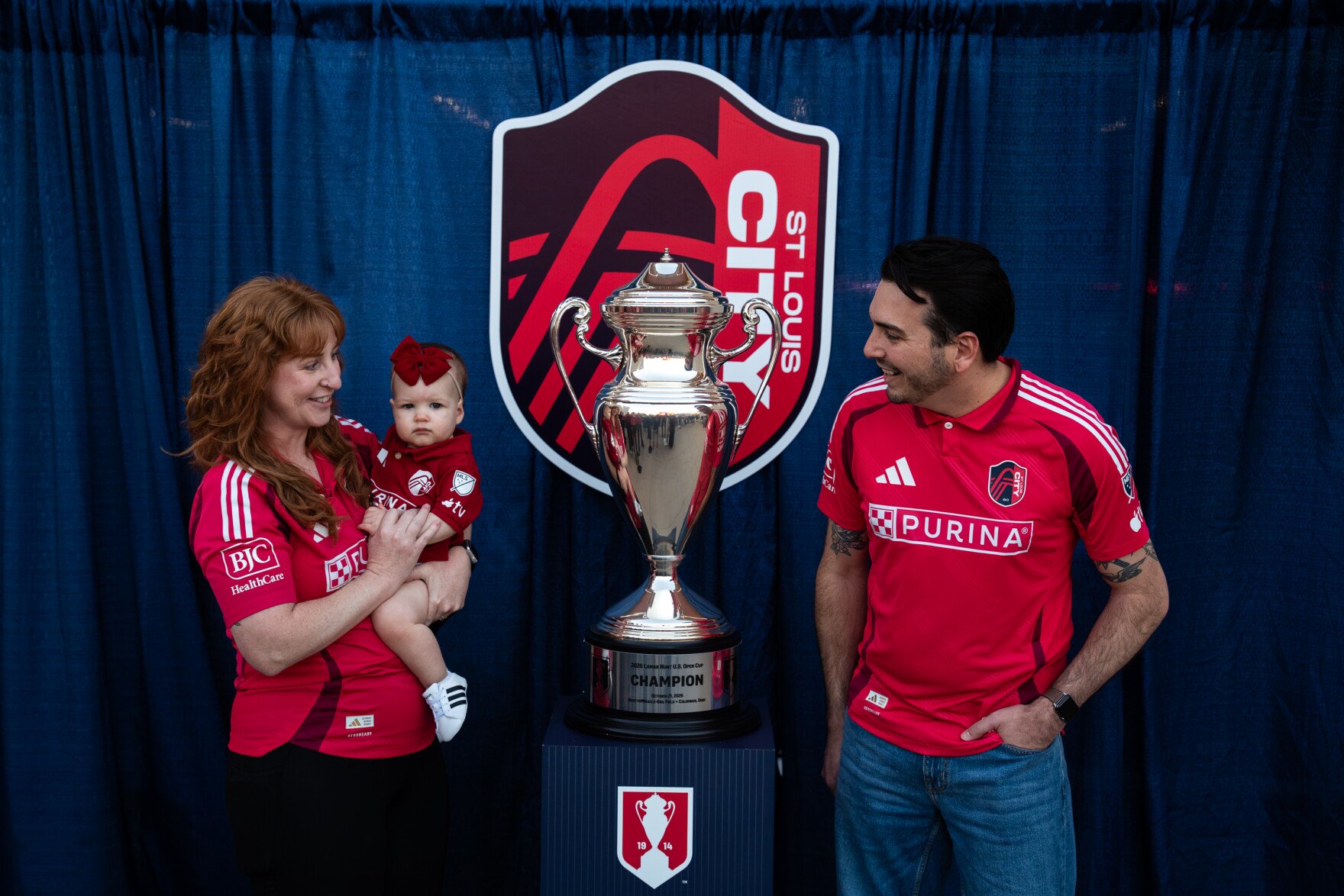 Gregory Cross, right, poses alongside his wife, Mary, and their 1-year-old daughter, Joey, with the Lamar Hunt U.S. Open Cup trophy outside Energizer Park on Wednesday, Oct. 28, 2026, in St. Louis’ Downtown West neighborhood.