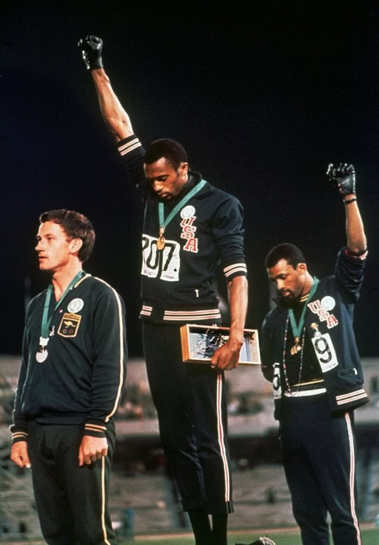 Extending gloved hands skyward in racial protest, US athletes Tommie Smith, center, and John Carlos stare downward after Smith received the gold and Carlos the bronze for the 200 meter run at the Summer Olympic Games in Mexico City