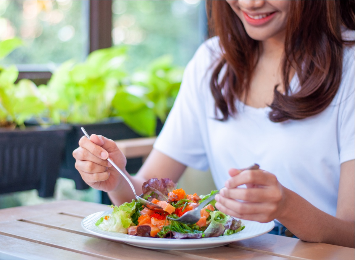 woman eating salmon salad and smiling