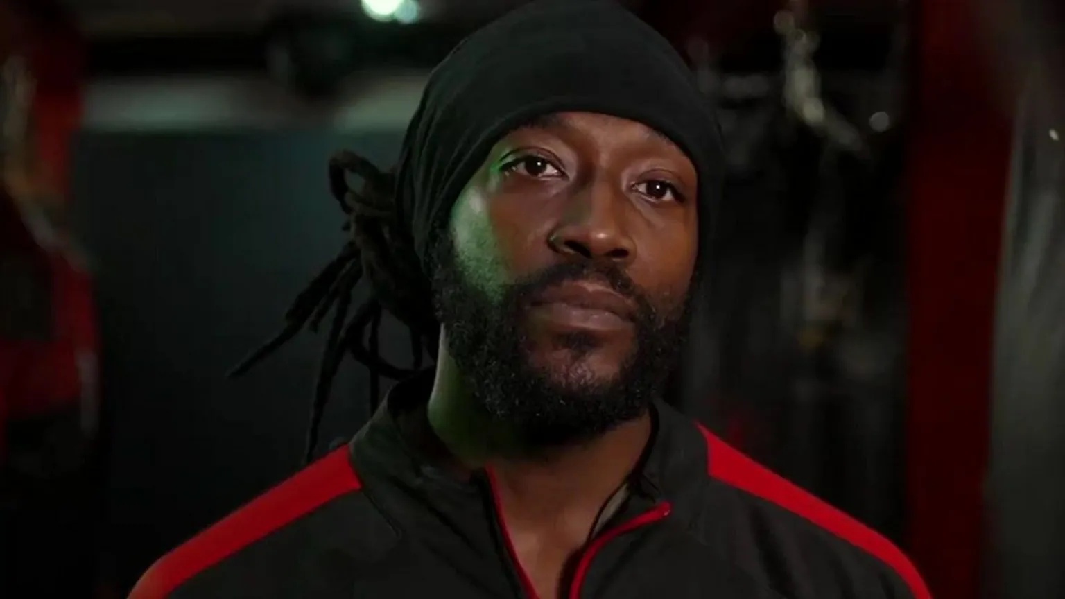 Marcus Luther in a boxing gym. He wears a black and red sports top.