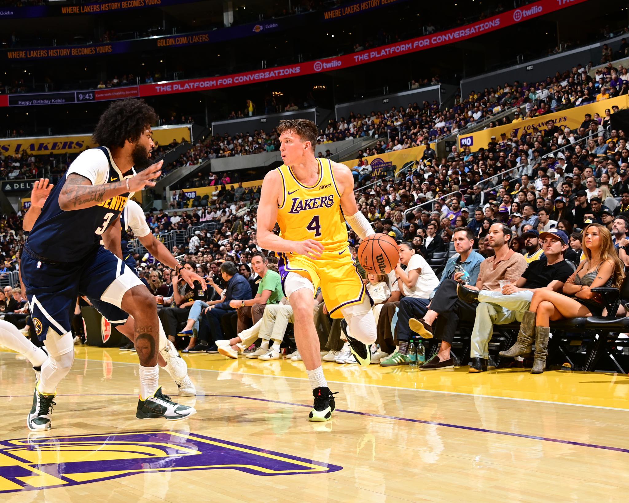 Dalton Knecht of the Los Angeles Lakers dribbles the ball past a Denver Nuggets defender during a game.