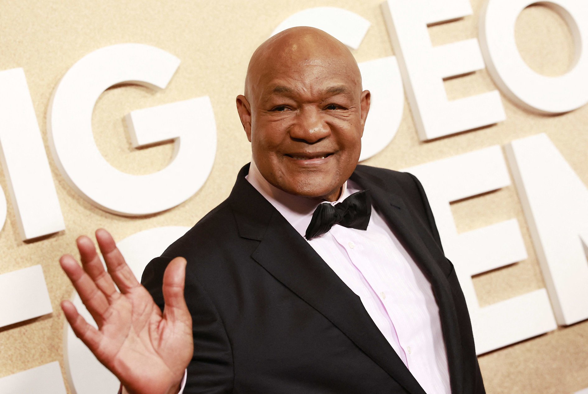 Retired pro-boxer George Foreman smiling and waving at a movie premiere.