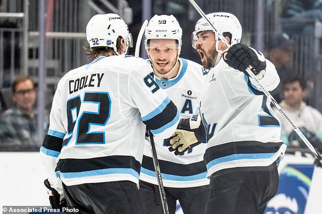 Utah Mammoth forward Logan Cooley, left, defenseman Mikhail Sergachev, middle, and defenseman MacKenzie Weegar celebrate a goal during the third periodof an NHL hockey game, Thursday, Oct. 22, 2026, in Seattle. (AP Photo/Stephen Brashear)
