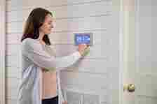 a woman using a digital thermostat