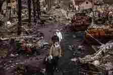 People walk through debris and destroyed Russian military vehicles on a street in Bucha, where Mykhed’s parents had been living at the start of the invasion (Getty Images)