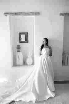 Black and White Portrait of Bride in Long Wedding Dress With Hair Down Posing Against Wall