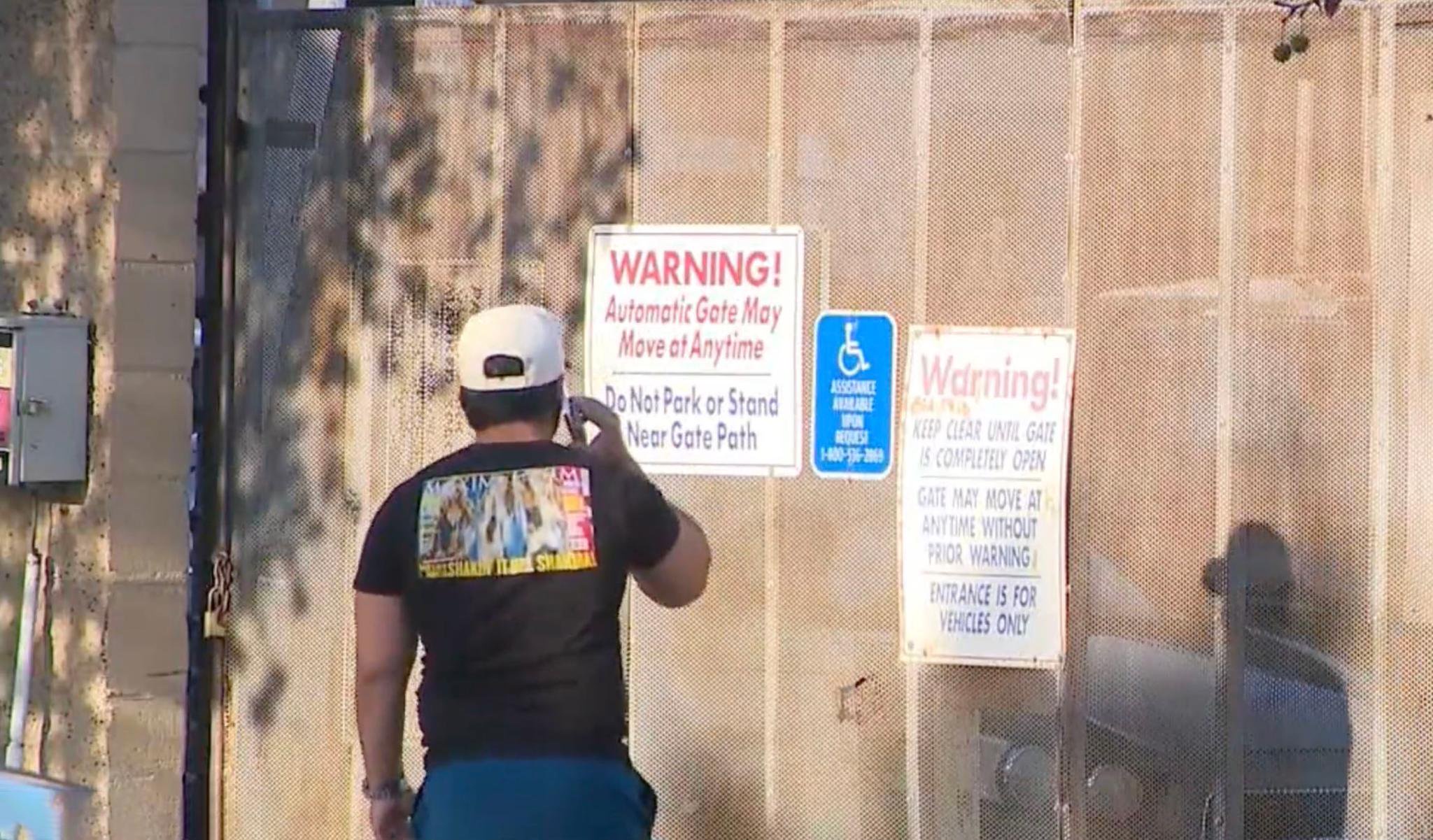 A runner stands in front of a metal gate with warning signs in San Ysidro.