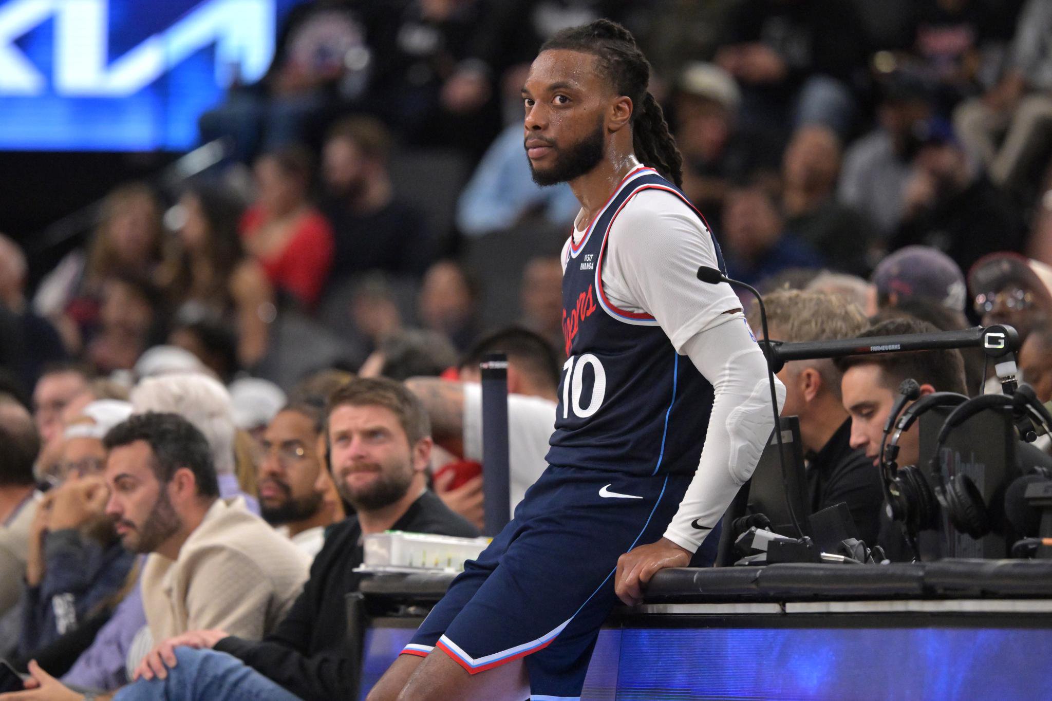 Los Angeles Clippers guard Darius Garland sits on the scorer's table, waiting to enter the game.