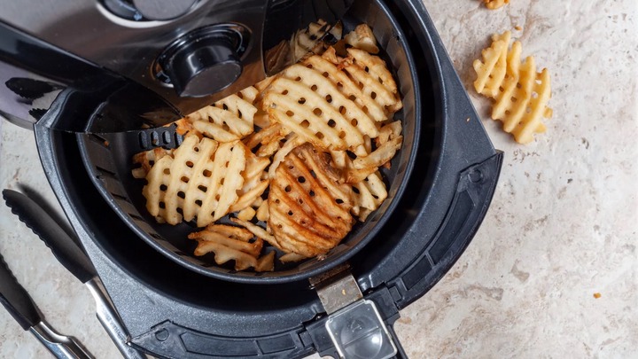 waffle fries in a black air fryer on a kitchen worktop