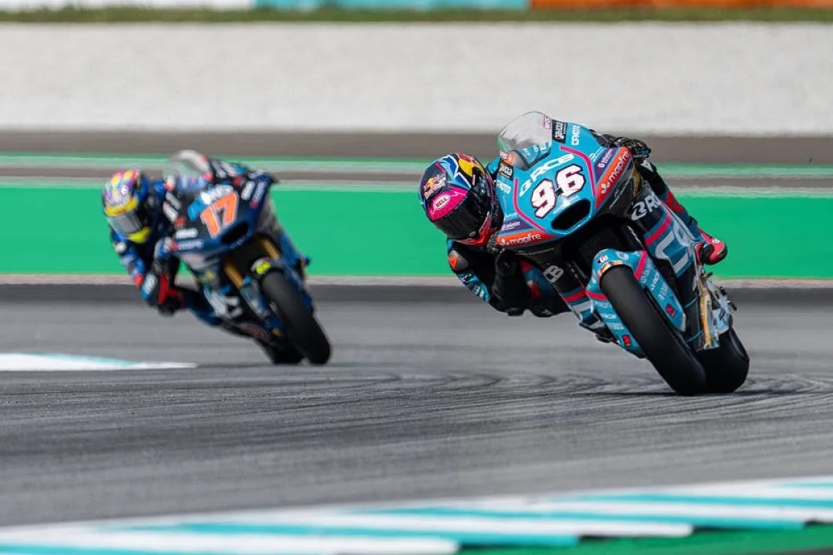 Moto2 rider wearing number 96 on a blue-and-pink bike leans into a corner at the Malaysian GP, chasing rider 17 ahead