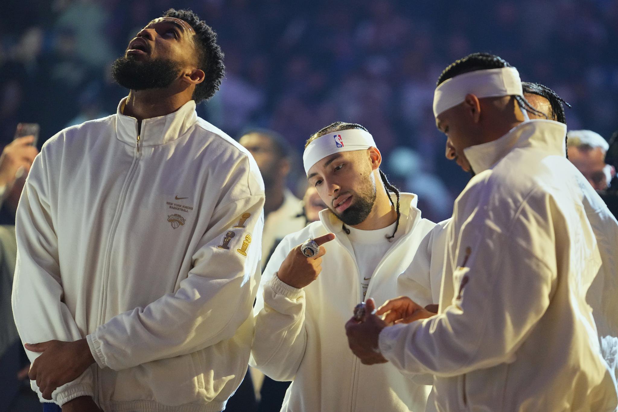 New York Knicks guard Jose Alvarado looks at his World Champions ring alongside teammates Karl-Anthony Towns and Josh Hart.