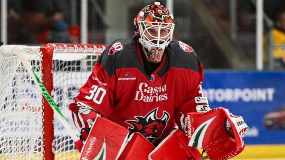Netminder Christian Stoever in helmet and red pads and Cardiff Devils jersey in front of net