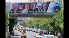 Vehicles move past a billboard displaying the faces of the six presidential candidates (L-R) Mohammad Bagher Ghalibaf, Amirhossein Ghazizadeh-Hashemi Alireza Zakani, Saeed Jalili, Mostafa Pourmohammadi and Masoud Pezeshkianin in the Iranian capital Tehran on June 29, 2024. Iran's sole reformist candidate Masoud Pezeshkian and ultraconservative Saeed Jalili are set to go to runoffs after securing the highest number of votes in Iran's presidential election, the interior ministry said. (Photo by ATTA KENARE / AFP) (AFP)