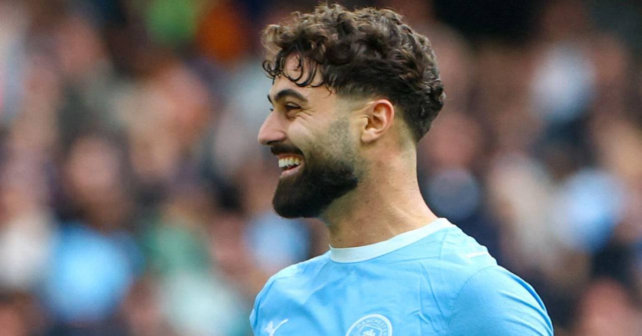 Croatia footballer Josko Gvardiol smiling while looking to his right and playing for Premier League team Manchester City Football Club in a light blue and white shirt with the club badge and Puma logo on the chest in a stadium