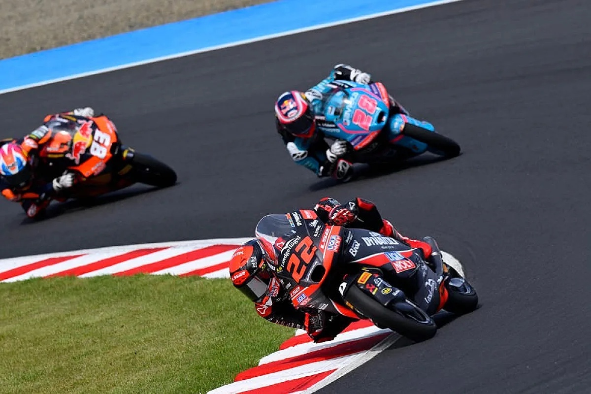 Rider number 22 leans into a corner on a red-and-black Moto3 bike, with rivals behind on a racetrack at Sepang practice.