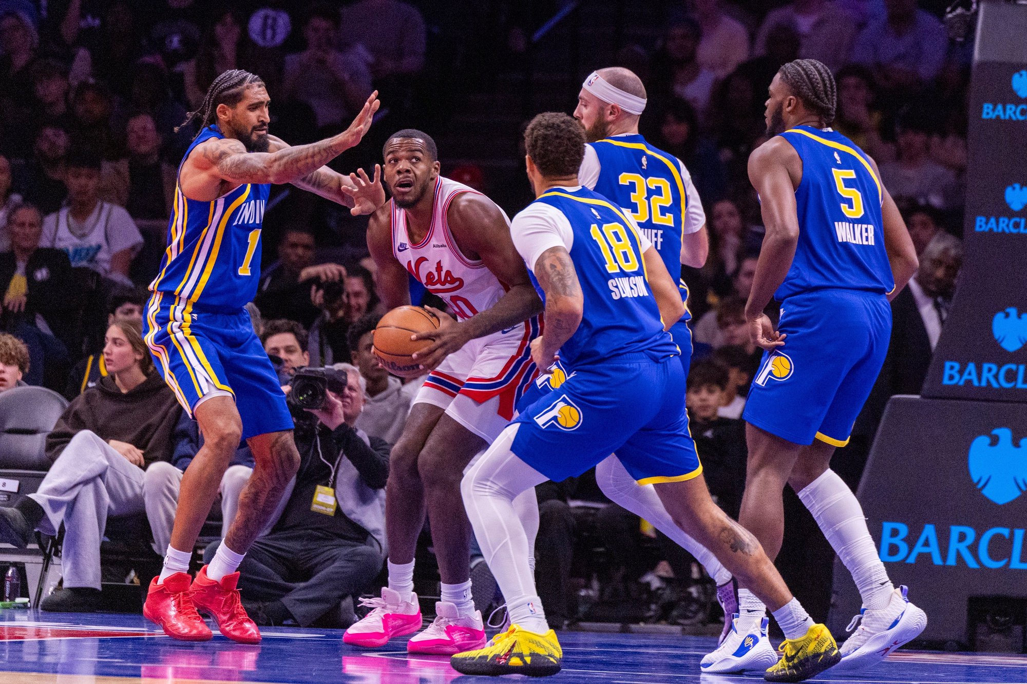 Brooklyn Nets center Day'ron Sharpe handles the ball while surrounded by Indiana Pacers defenders during a game.