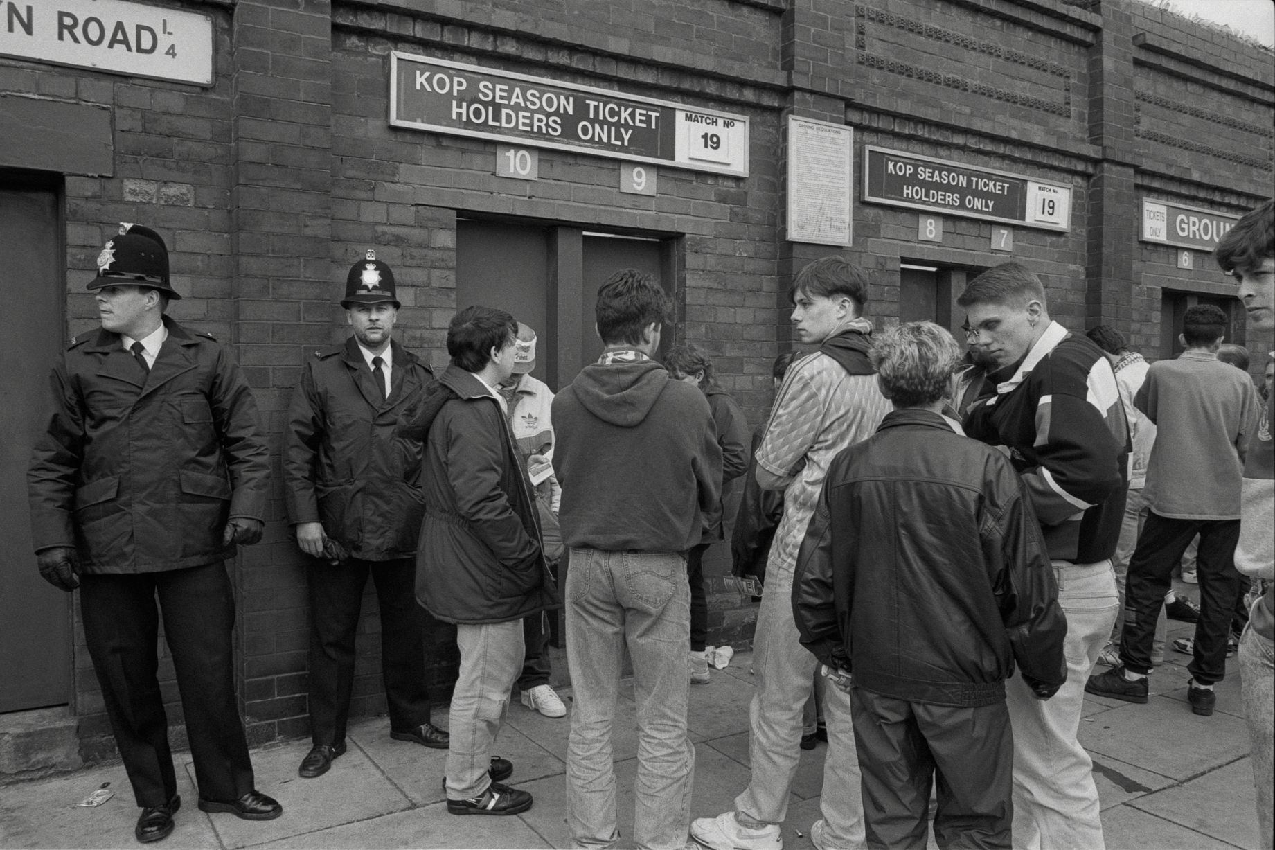 In 1991, photographer Richard Davis followed supporters from across the North West for a book about football, fashion and music. Richard spent much of the season taking pictures of fans from Liverpool, Everton and more for the book Football With Attitude. In collaboration with Lower Block, the Going to the Match zine has been published to coincide with an exhibition of the same name at Bury Art Museum, running from October 2024 to March 2025.
Pictured: Outside Anfield, 1991