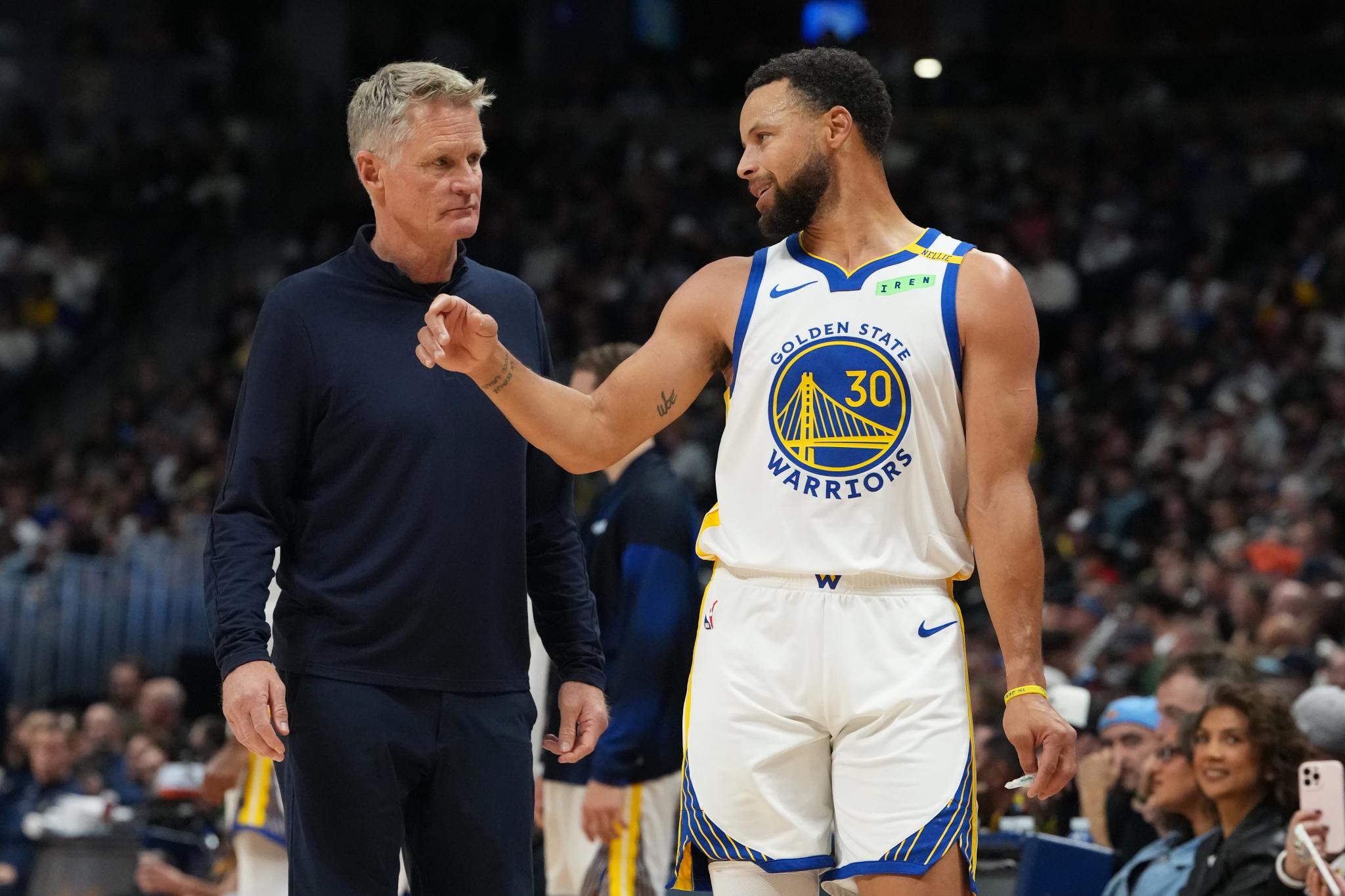 Golden State Warriors guard Stephen Curry confers with head coach Steve Kerr during a game.