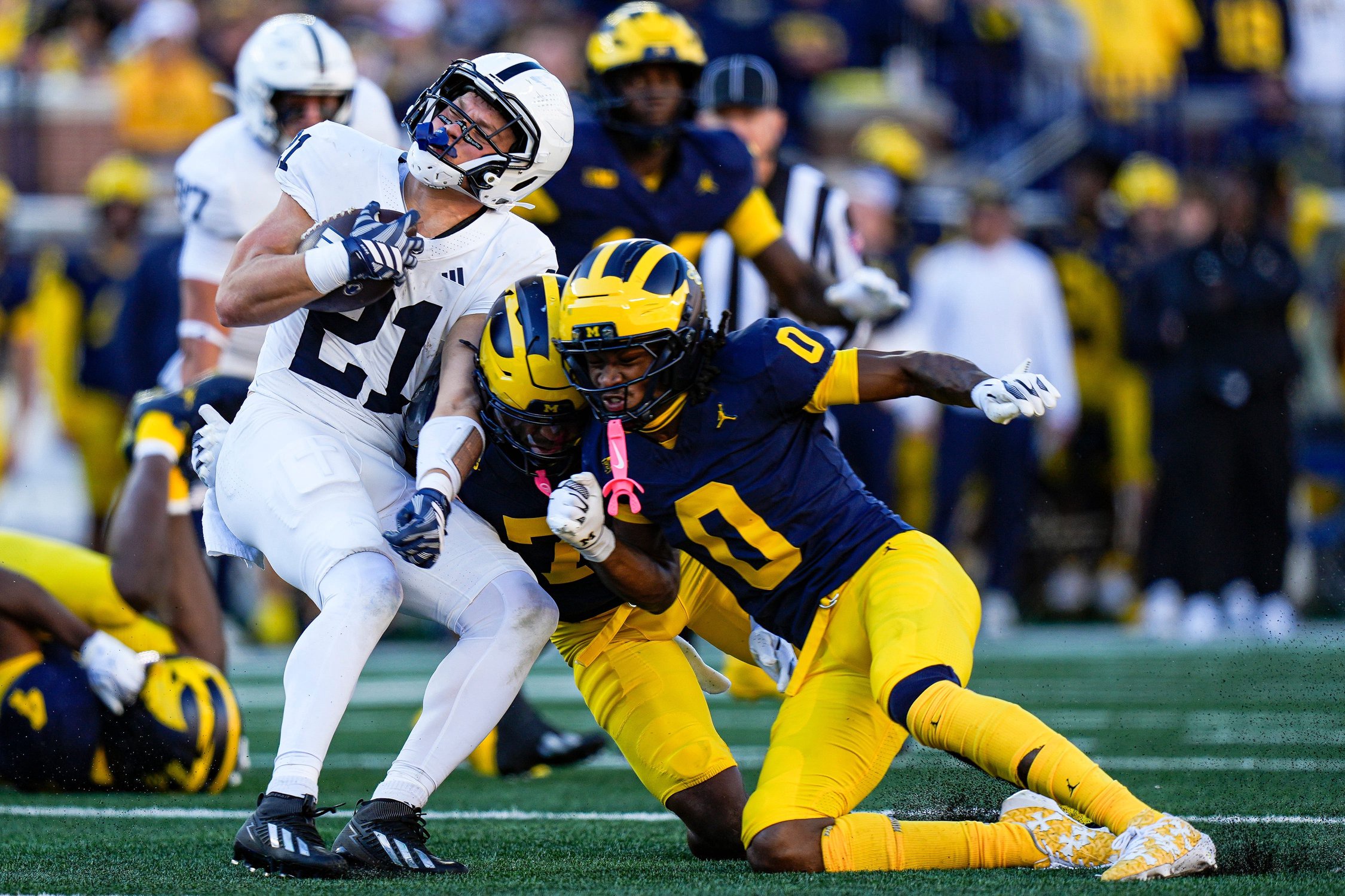 Michigan safety Chris Bracy (7) and cornerback Jyaire Hill (0) tackle Penn State running back Carson Hansen (21) during the first half at Michigan Stadium in Ann Arbor on Saturday, Oct. 17, 2026.