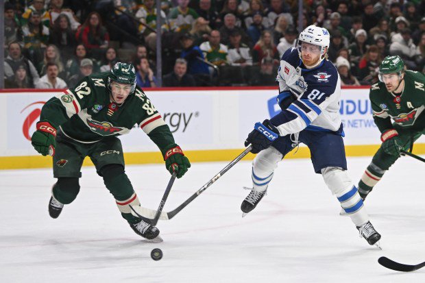 Winnipeg wing Kyle Connor (81) hits the puck past the Wild defenseman David Spacek (82) during the first period of the Jets' 6-2 victory on Thursday, Jan. 15, 2028, at Grand Casino Arena. (Craig Lassig / Associated Press)