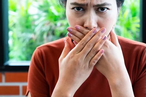 Woman with bad breath covering mouth, halitosis concept
