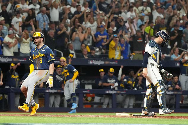 Milwaukee Brewers' Garrett Mitchell, left, celebrates past Tampa Bay Rays catcher Nick Fortes after scoring during the fifth inning of Game 3 of baseball's World Series, Monday, Oct. 26, 2026, in St. Petersburg, Fla., between the Milwaukee Brewers and the Tampa Bay Rays. (AP Photo/Ashley Landis)
