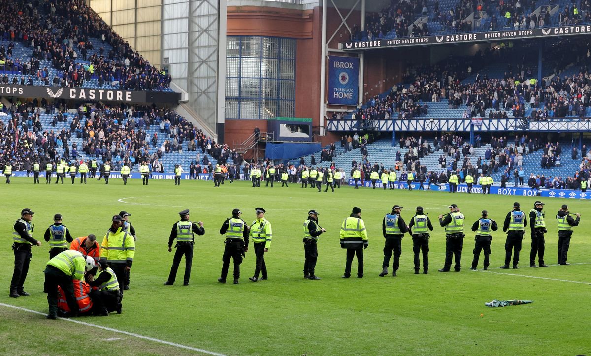 Police officer and stewards form a line to separate the fans following the penalty shoot out after the Scottish Gas Men's Scottish Cup quarter-final match at Ibrox Stadium