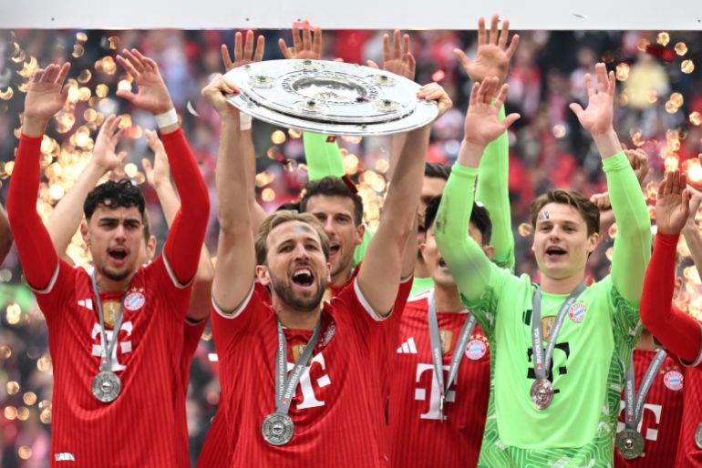 Bayern Munich's Harry Kane lifts the trophy as he celebrates with teammates after winning the Bundesliga