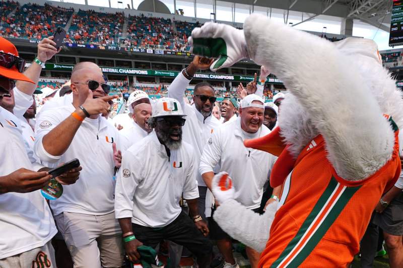 Members of Miami's 2001 national championship team celebrate with Miami mascot Sebastian the Ibis as they are honored at halftime.