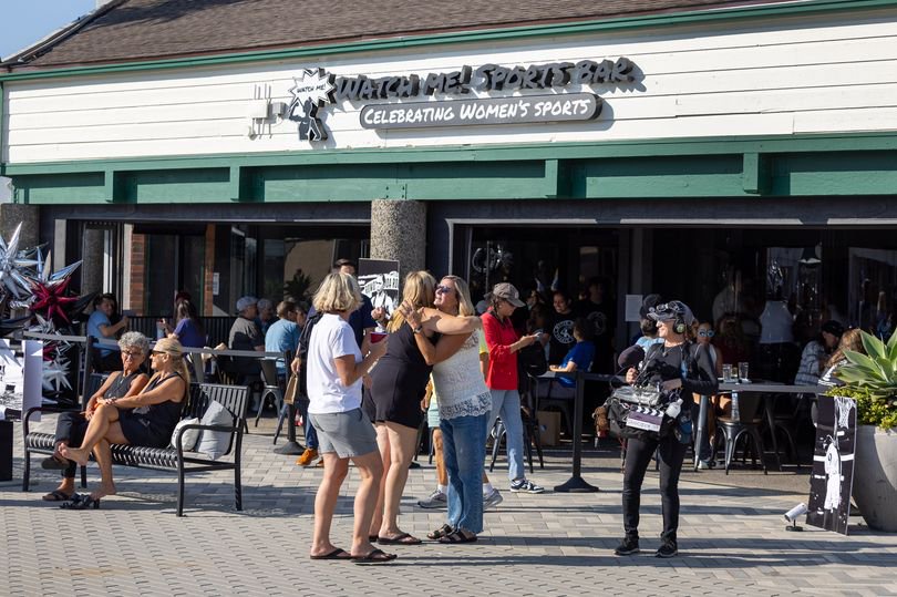Patrons greet each other as they arrive at the bar, ordering food and drinks and watching women's sports during the grand opening of Watch Me! Sports Bar in Long Beach Friday, July 26, 2024