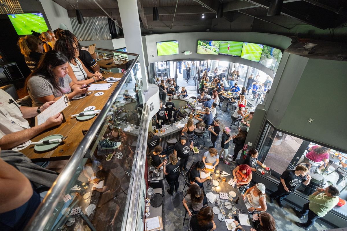 Patrons fill the bar, ordering food and drinks and watching women's sports during the grand opening of Watch Me! Sports Bar in Long Beach Friday, July 26, 2024
