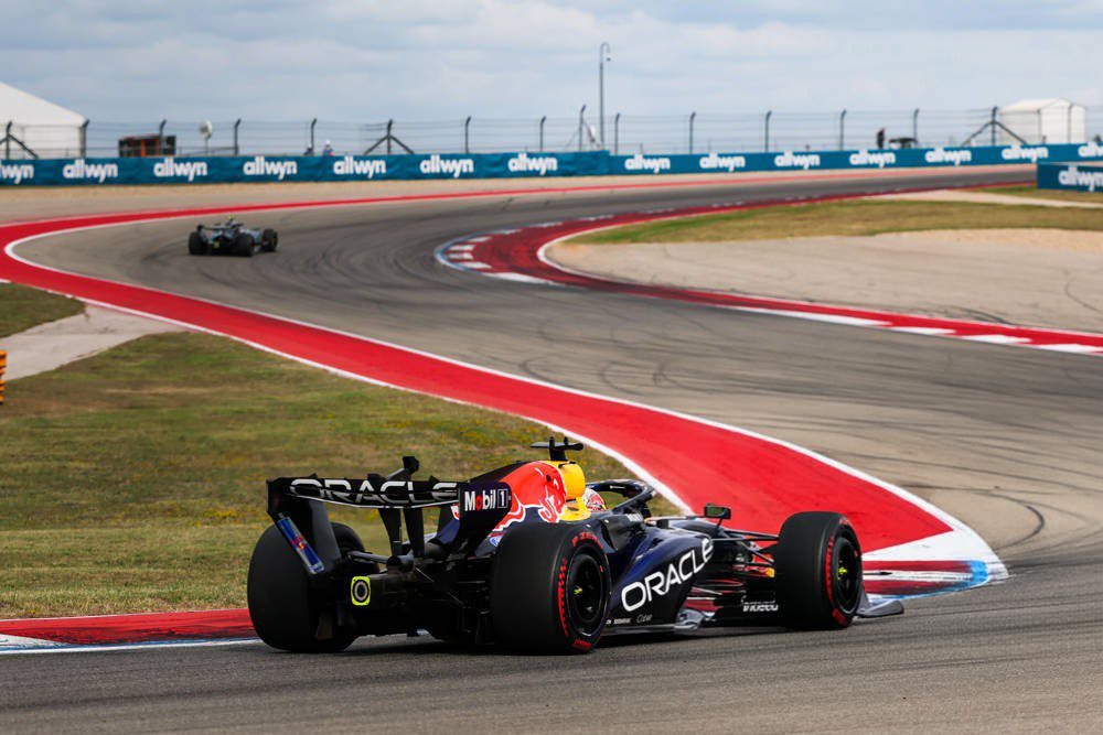 Max Verstappen's Red Bull RB22 with Oracle livery racing on a Formula 1 circuit with red-and-white kerbs