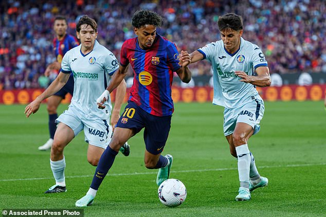 Barcelona's Lamine Yamal, centre, challenges for the ball with Getafe's Ramon Terrats, right, during the Spanish La Liga soccer match between Barcelona and Getafe in Barcelona, Spain, Saturday, Oct. 10, 2026. (AP Photo/Joan Monfort)