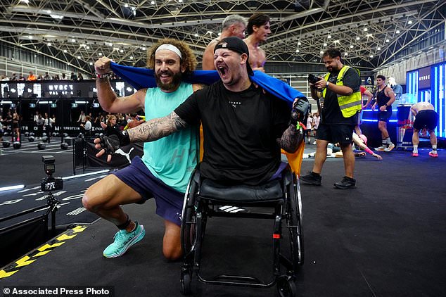 Ukrainian veterans Oleh Tserkovnyy, left, and Dmytro Bykhovchenko celebrate on the finish line during the HYROX competition in Valencia, Spain, Sunday, Oct. 18, 2026. (AP Photo/Alberto Sáiz)