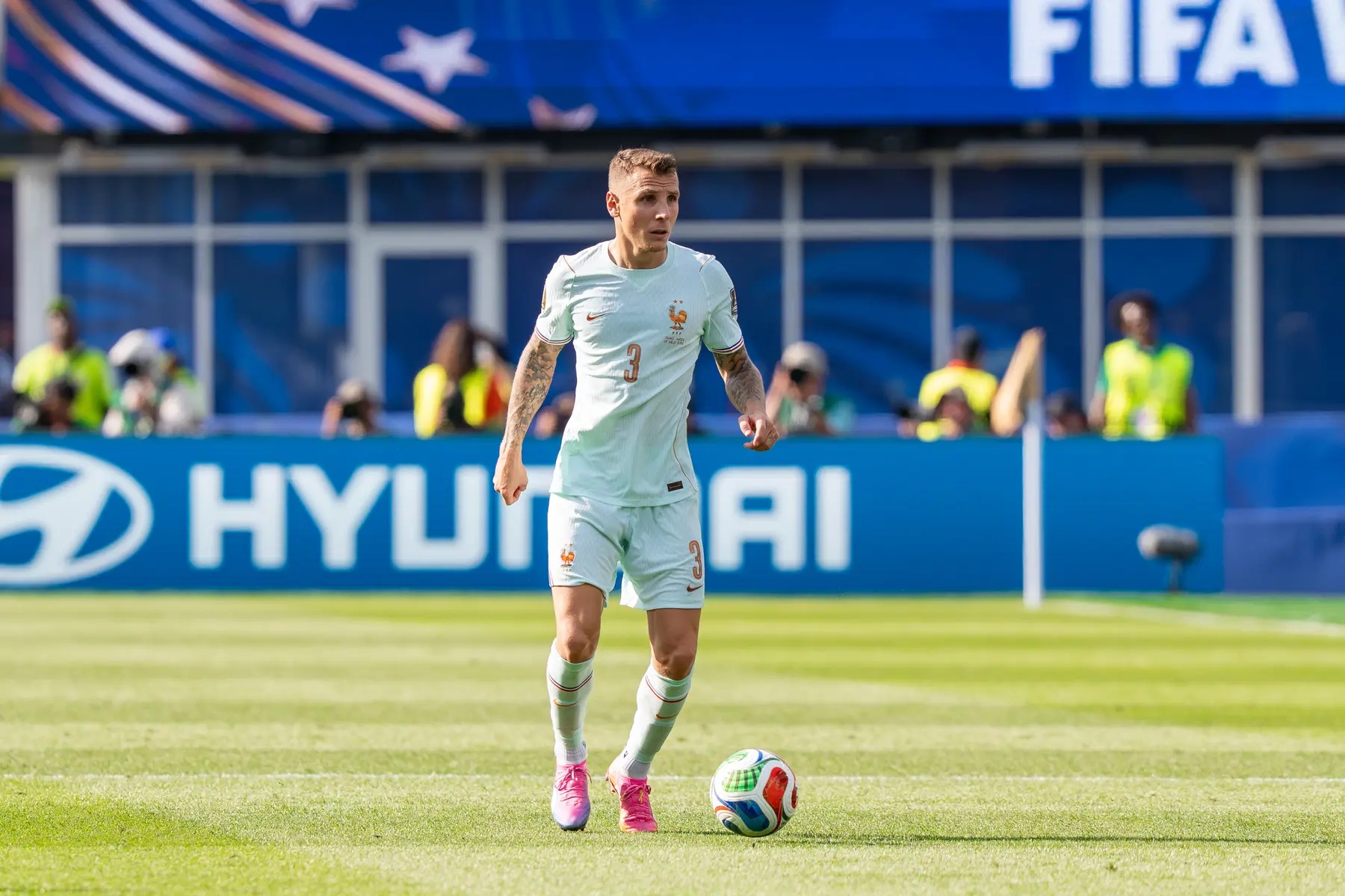 Lucas Digne in a white France national team kit with a football at his feet during a match.