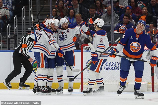 From left, Edmonton Oilers' Connor McDavid, Vasily Podkolzin, Leon Draisaitl and Evan Bouchard react after Podkolzin scored a goal during the second period of an NHL hockey game against the New York Islanders Saturday, Oct. 31, 2026, in Elmont, N.Y. (AP Photo/Pamela Smith)