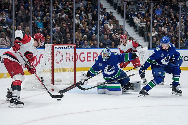 Vancouver Canucks goaltender Leevi Merilainen (31) stops Carolina Hurricanes' Andrei Svechnikov (37) as Vancouver's Elias Pettersson (25) watches during the second period of an NHL hockey game in Vancouver on Tuesday, Oct. 20, 2026. (Ethan Cairns/The Canadian Press via AP)