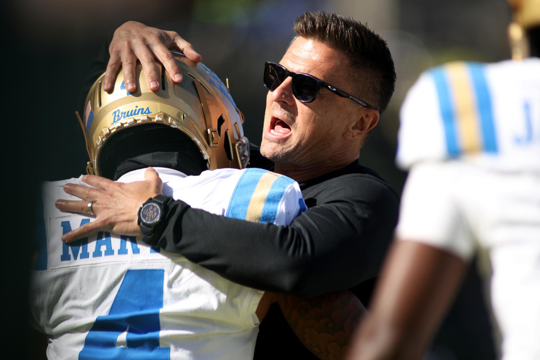 Bob Chesney embraces Cole Martin on the football field.