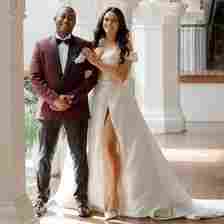 Bride in Wedding Dress Posing With Groom in Maroon Tuxedo in Archway 