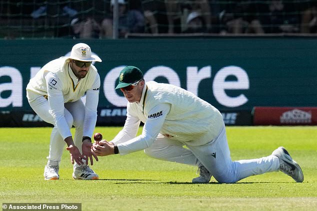 South Africa's Simon Harmer, right, attempts to field the ball as South Africa's Aiden Markram covers him on day five of the second cricket test match between South Africa and Australia, in Gqeberha, South Africa, Thursday, Oct. 22, 2026. (AP Photo/Themba Hadebe)