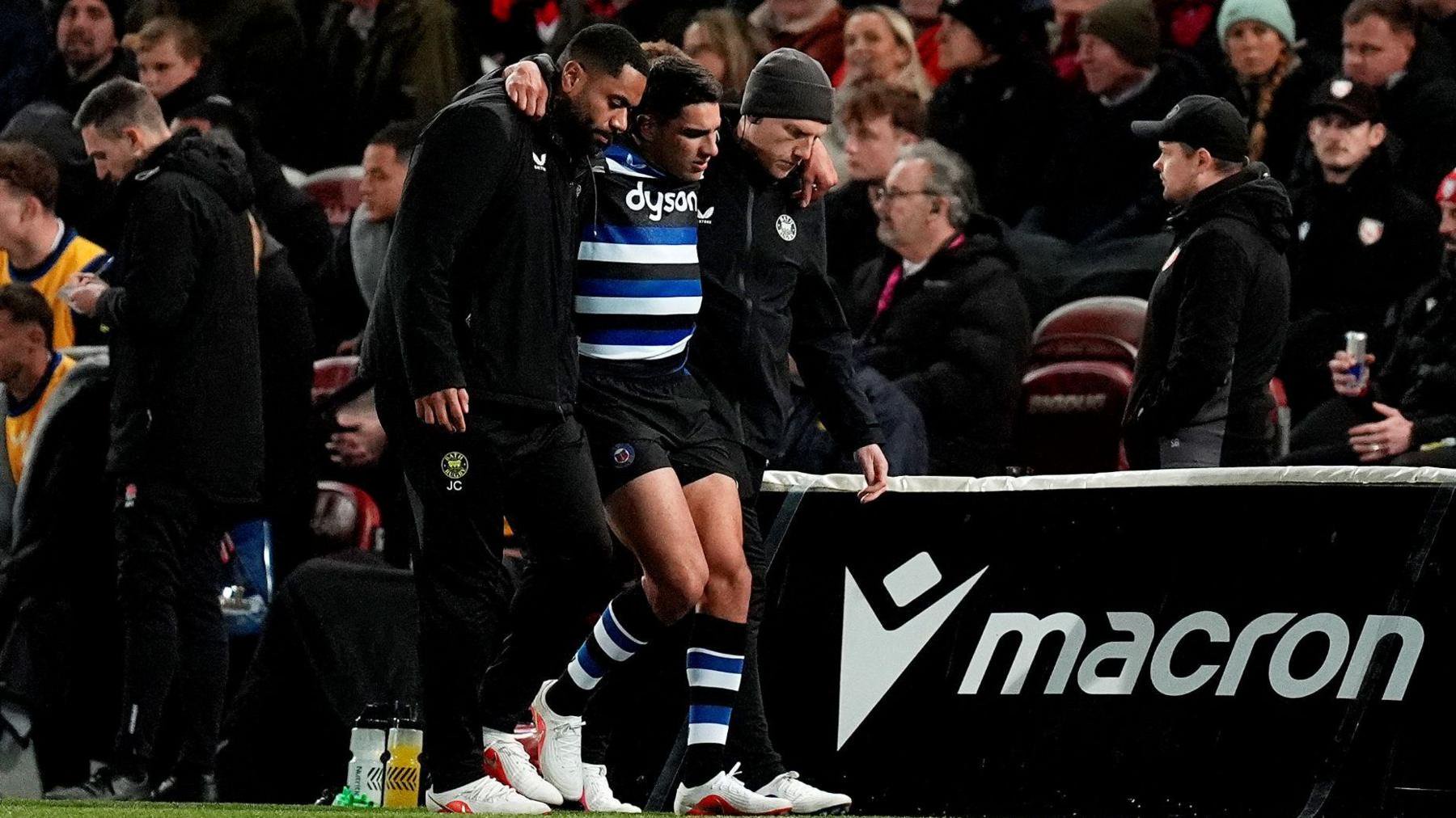 Santiago Carreras (centre) walks off the pitch with his arms around two people